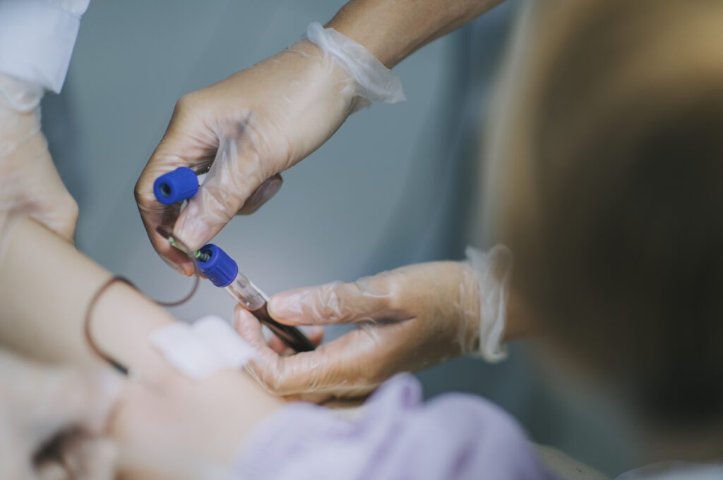 close up asian chinese nurse drawing blood from female chinese patient arm's vein in the clinic