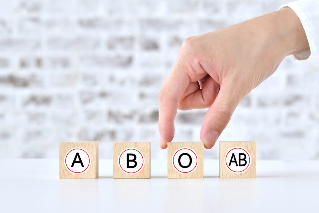 Human's hand picking up wooden blocks with blood type alphabet
