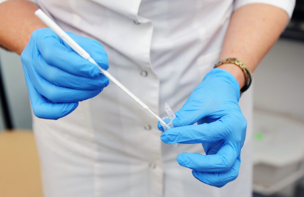 A gynecologist in blue gloves is taking an analysis for research. Gynecologist taking a smear.