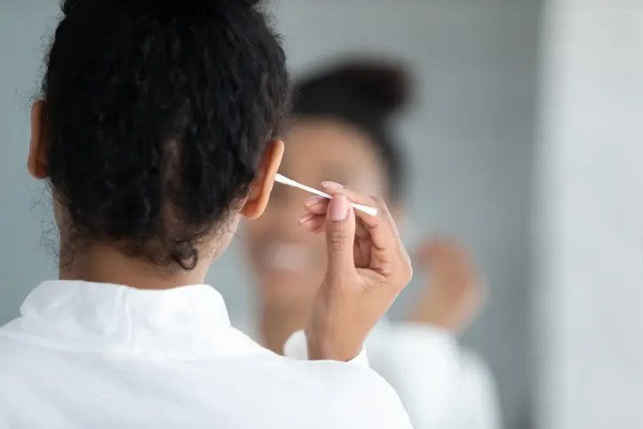 A woman using a Q-Tip to remove earwax